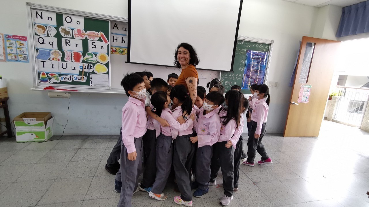 Teacher in a blue shirt standing with several students in pink shirts.