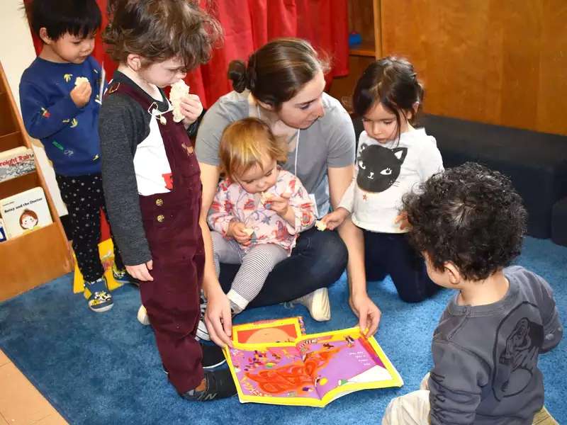 A student reads a picture book to 5 toddlers